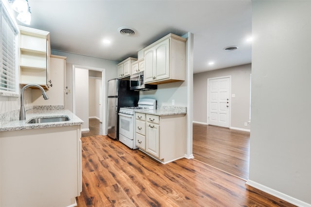 2018 Shawnee St, Denton, TX 76209 - kitchen with appliances with stainless steel finishes, a sink, open shelves, wood finished floors, and recessed lighting