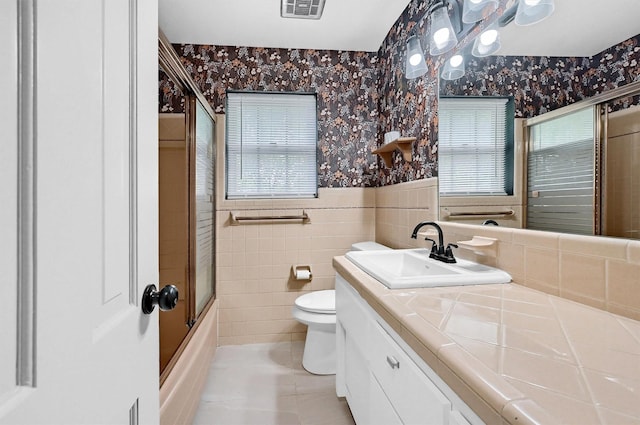 506 Melody Ln, Gainesville, TX 76240 - full bath with wallpapered walls, toilet, a wainscoted wall, vanity, and tile walls