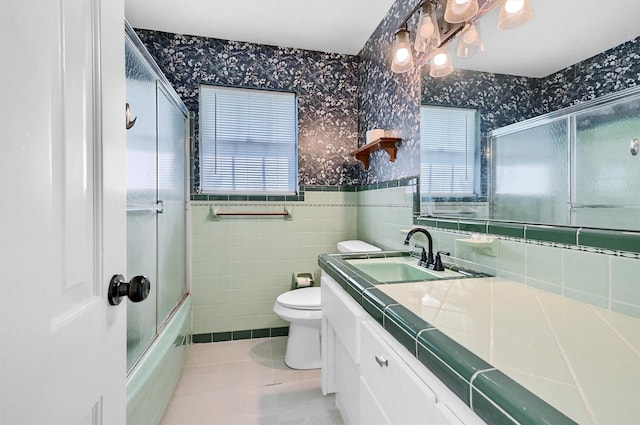 506 Melody Ln, Gainesville, TX 76240 - full bath with wallpapered walls, healthy amount of natural light, toilet, a wainscoted wall, and vanity