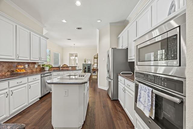 508 Wellington Rd, Coppell, TX 75019 - kitchen featuring appliances with stainless steel finishes, a center island, ornamental molding, white cabinetry, and recessed lighting