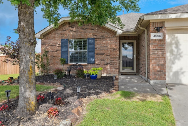 14065 Tanglebrush Trl, Fort Worth, TX 76052 - view of exterior entry with brick siding, a shingled roof, and a garage