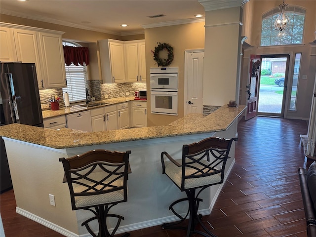 135 Freedom Ct, Rockwall, TX 75032 - kitchen featuring white appliances, a sink, decorative backsplash, white cabinets, and a breakfast bar