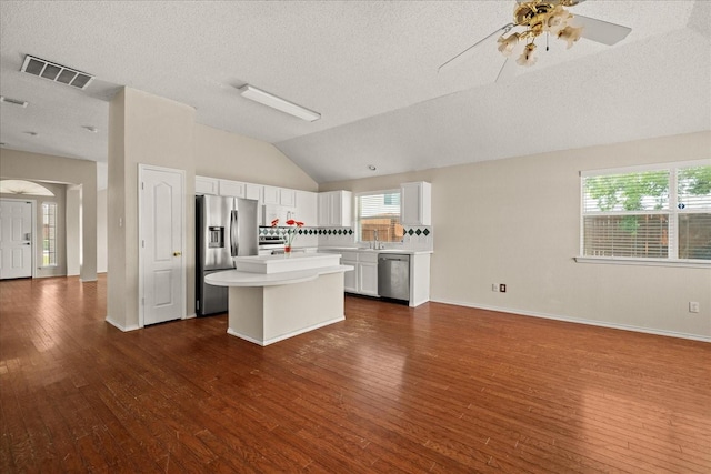 1214 Meadowbend Ct, Allen, TX 75002 - kitchen with stainless steel appliances, light countertops, dark wood-type flooring, vaulted ceiling, and a center island