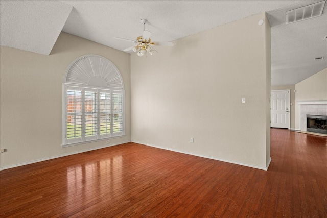 1214 Meadowbend Ct, Allen, TX 75002 - empty room with vaulted ceiling, wood finished floors, a ceiling fan, a fireplace, and a textured ceiling