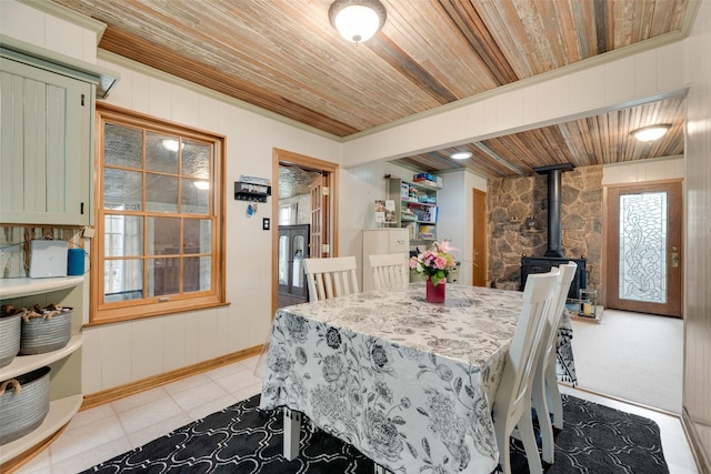 1606 S Jefferson St, Kaufman, TX 75142 - dining room with wooden ceiling, a wood stove, light tile patterned flooring, wooden walls, and baseboards