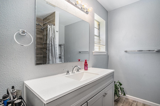 629 Barbara Ln, Burleson, TX 76028 - bathroom with wood finished floors, a textured wall, vanity, baseboards, and tiled shower