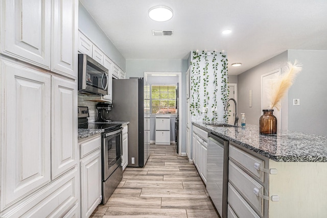 629 Barbara Ln, Burleson, TX 76028 - kitchen with stainless steel appliances, a sink, light wood-style flooring, decorative backsplash, and a peninsula
