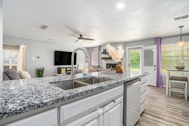 629 Barbara Ln, Burleson, TX 76028 - kitchen featuring a sink, a fireplace, ceiling fan, dishwasher, and dark stone counters