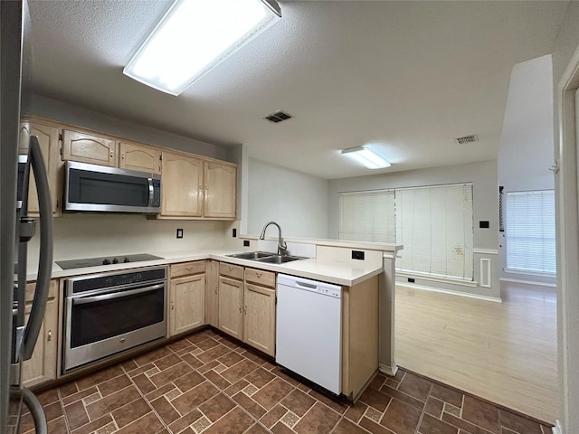 2114 Montclair Ln, Lewisville, TX 75067 - kitchen with appliances with stainless steel finishes, a sink, light brown cabinetry, and a peninsula