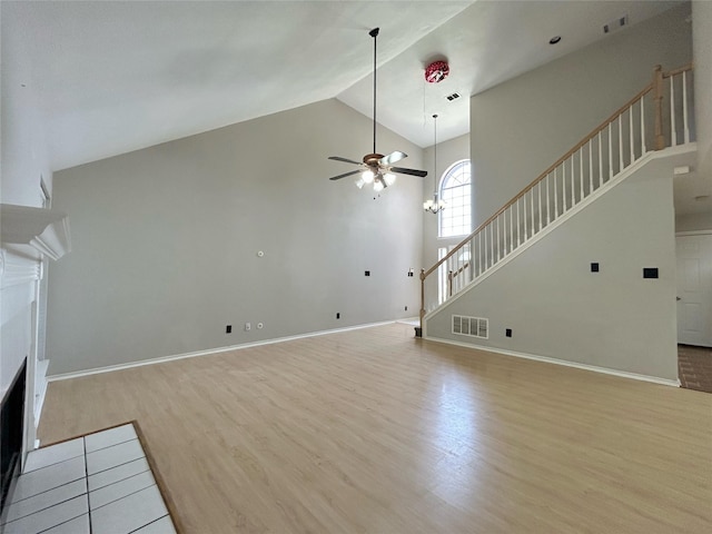 2114 Montclair Ln, Lewisville, TX 75067 - unfurnished living room with ceiling fan, wood finished floors, high vaulted ceiling, a fireplace with flush hearth, and stairway