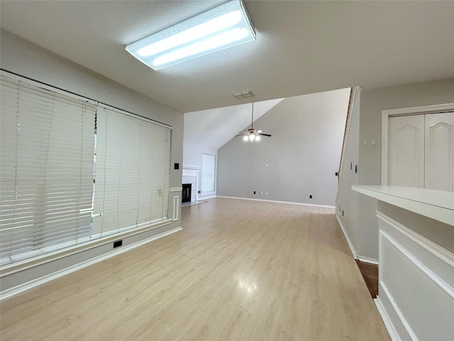 2114 Montclair Ln, Lewisville, TX 75067 - unfurnished living room with wood finished floors, lofted ceiling, ceiling fan, baseboards, and a fireplace with flush hearth