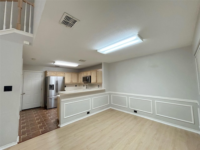 2114 Montclair Ln, Lewisville, TX 75067 - kitchen with stainless steel appliances, light brown cabinetry, a peninsula, light countertops, and dark wood-style floors