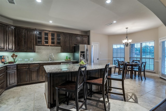 611 Southwestern Dr, Rockwall, TX 75087 - kitchen featuring stainless steel refrigerator with ice dispenser, a sink, light stone countertops, backsplash, and a breakfast bar area