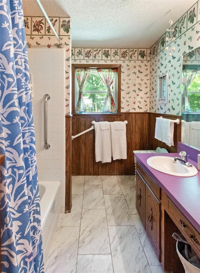 full bath featuring a textured ceiling, marble finish flooring, vanity, wooden walls, and shower / bath combination with curtain