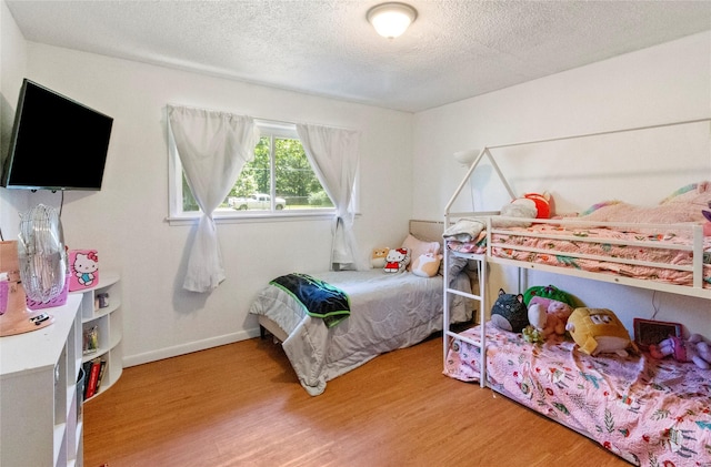 bedroom with light wood-style flooring, a textured ceiling, and baseboards