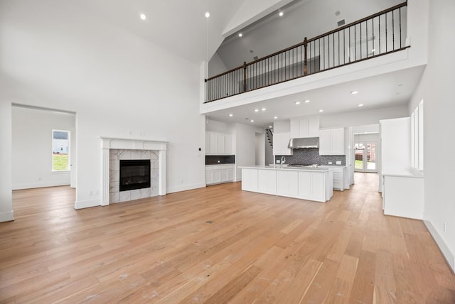 1758 Cousins Trl, Frisco, TX 75034 - unfurnished living room featuring light wood-style floors, a high ceiling, plenty of natural light, a sink, and a fireplace
