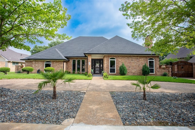 509 Farine Dr, Irving, TX 75062 - french country home featuring roof with shingles, brick siding, a chimney, and a front yard