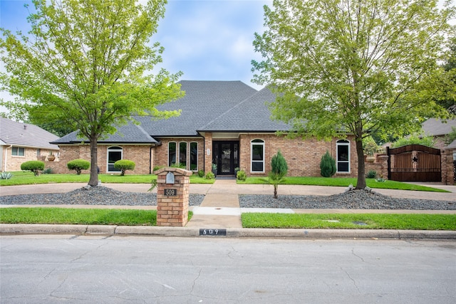 509 Farine Dr, Irving, TX 75062 - french provincial home featuring a shingled roof, brick siding, and a gate