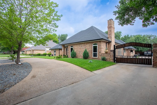 509 Farine Dr, Irving, TX 75062 - view of home's exterior featuring roof with shingles, a gate, concrete driveway, a chimney, and a yard