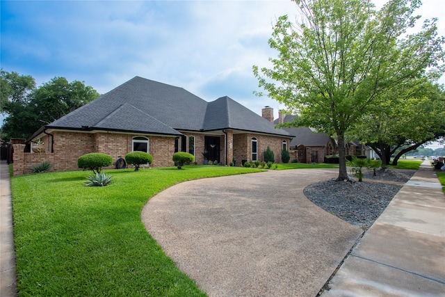 509 Farine Dr, Irving, TX 75062 - french country home with a shingled roof, brick siding, a front yard, a chimney, and curved driveway