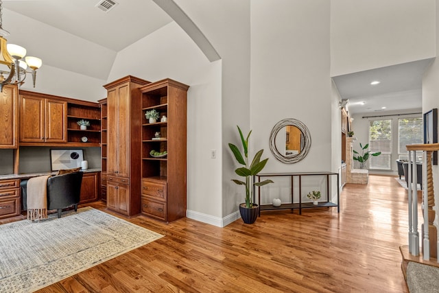 office with built in desk, arched walkways, light wood finished floors, high vaulted ceiling, and baseboards