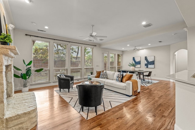 living room with ceiling fan, arched walkways, ornamental molding, baseboards, and light wood-type flooring