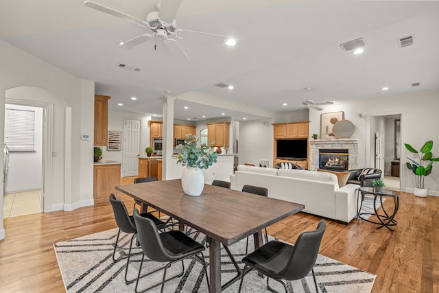 dining area featuring ceiling fan, baseboards, light wood finished floors, a stone fireplace, and recessed lighting