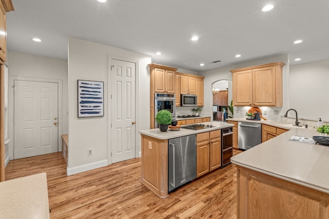 kitchen featuring stainless steel appliances, a sink, light wood-style flooring, light countertops, and recessed lighting