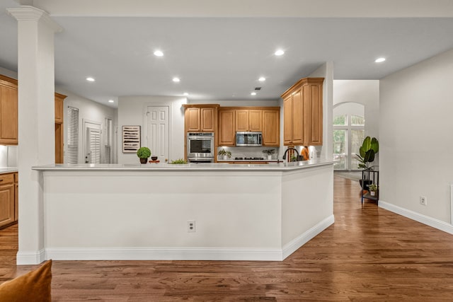kitchen featuring stainless steel appliances, wood finished floors, baseboards, recessed lighting, and light countertops