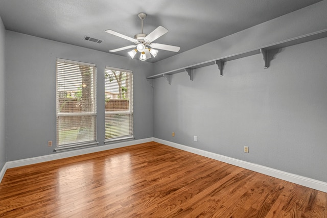 empty room with baseboards, wood finished floors, and a ceiling fan