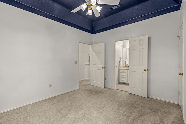 unfurnished bedroom with light colored carpet, connected bathroom, baseboards, a towering ceiling, and a ceiling fan