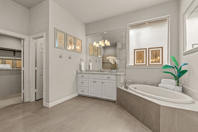 bathroom featuring a bath, vanity, and a chandelier