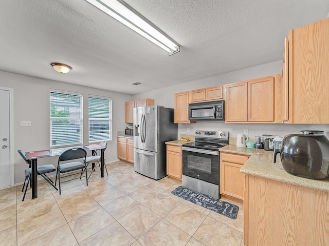 9228 Cheswick Dr, Fort Worth, TX 76123 - kitchen with stainless steel appliances, light brown cabinets, a textured ceiling, and light tile patterned floors