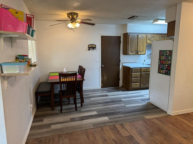 419 Travis St, Ranger, TX 76470 - dining space with ceiling fan, baseboards, wood finished floors, and a textured ceiling