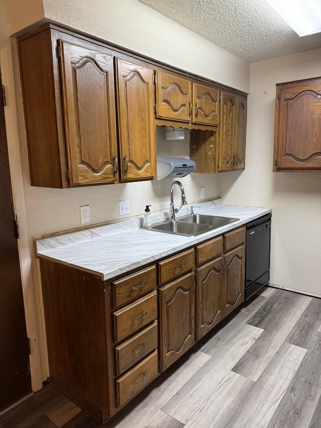 419 Travis St, Ranger, TX 76470 - kitchen with black dishwasher, a sink, light wood-style floors, light countertops, and a textured ceiling
