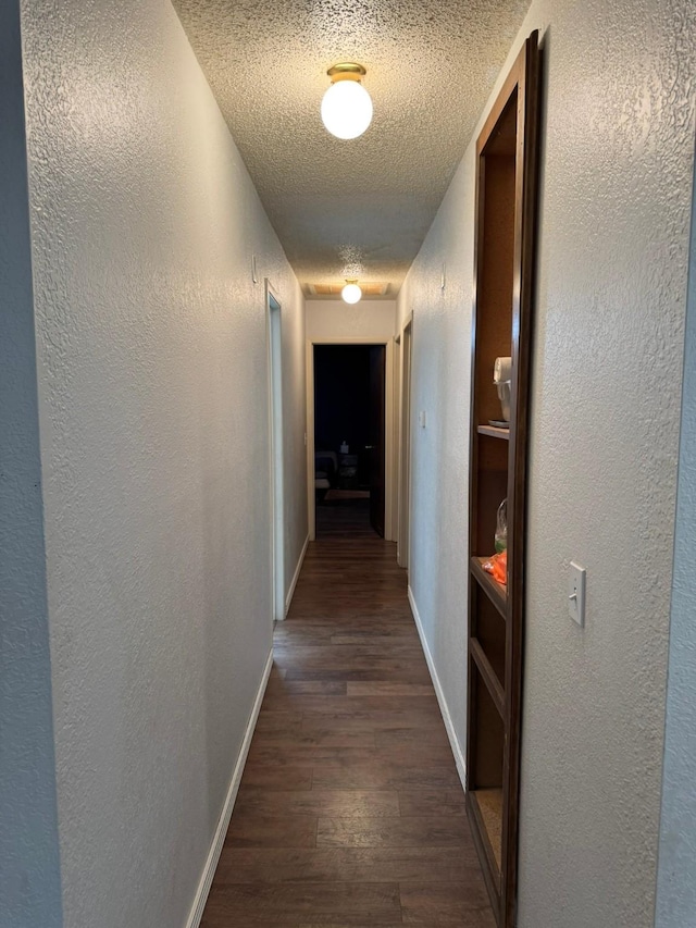 419 Travis St, Ranger, TX 76470 - hall featuring a textured ceiling, baseboards, dark wood finished floors, and a textured wall