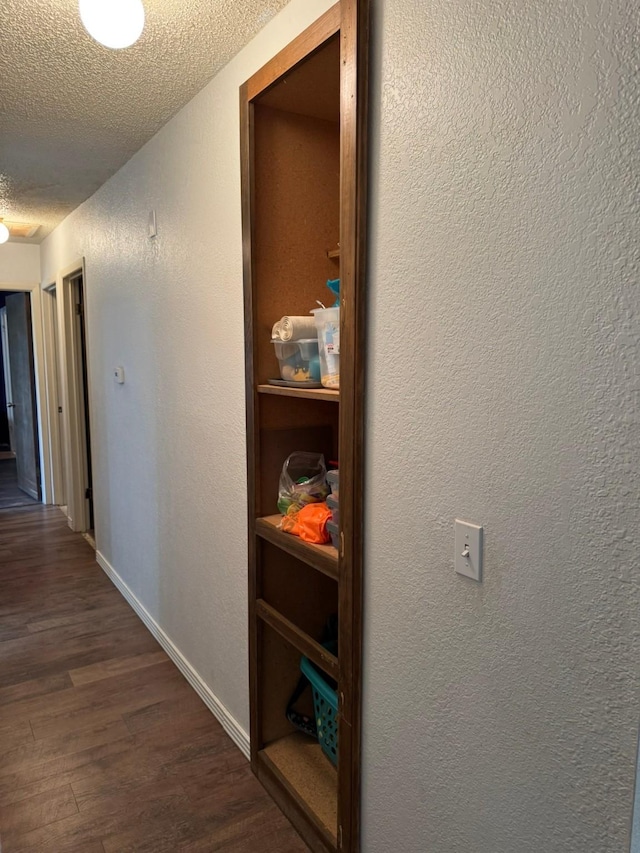 419 Travis St, Ranger, TX 76470 - hallway with a textured ceiling, dark wood-style floors, a textured wall, and baseboards