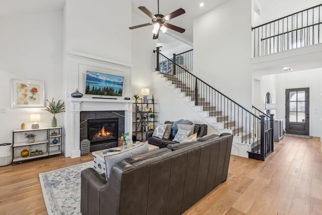 2171 Cloverfern Way, Haslet, TX 76052 - living area with a towering ceiling, stairway, a glass covered fireplace, a ceiling fan, and light wood finished floors
