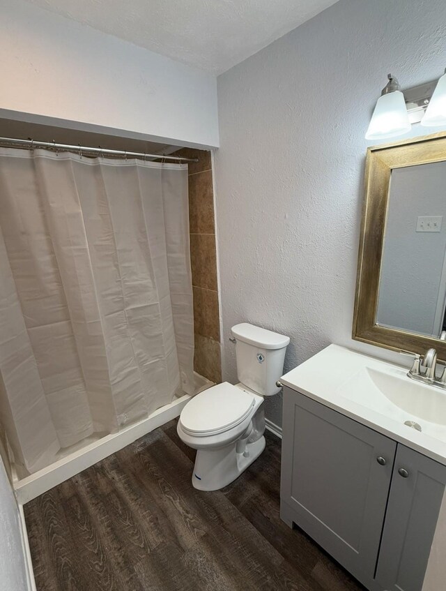 553 Oldbridge Dr, Allen, TX 75002 - full bathroom with wood finished floors, tiled shower, toilet, vanity, and a textured wall