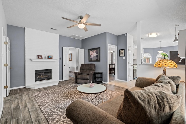 6706 Trumpet Dr, Rowlett, TX 75089 - living area featuring wood finished floors, ceiling fan, a textured ceiling, a brick fireplace, and baseboards