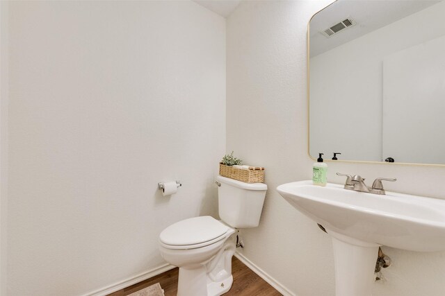 7536 Brentwood Stair Rd, Fort Worth, TX 76112 - half bath featuring wood finished floors, toilet, baseboards, and a sink