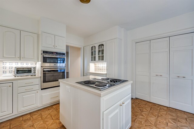 3437 Purdue St, University Park, TX 75225 - kitchen with stainless steel appliances, white cabinets, light countertops, a kitchen island, and glass insert cabinets