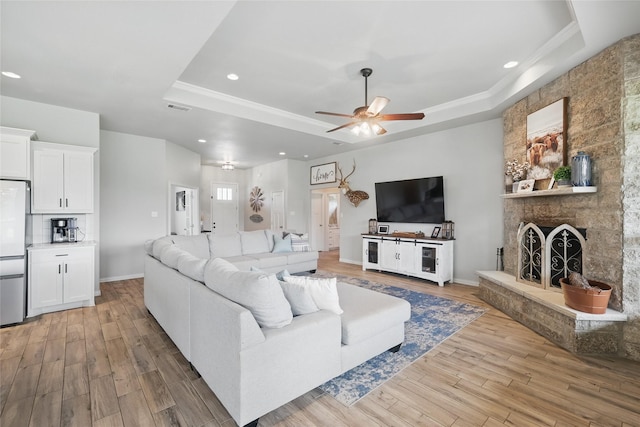115 Lavender Ln, Springtown, TX 76082 - living room featuring a raised ceiling, ceiling fan, light wood-style floors, recessed lighting, and a stone fireplace