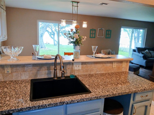 650 Sp Terry Rd, Belton, TX 76513 - kitchen with a sink, open floor plan, hanging light fixtures, white cabinetry, and light stone counters
