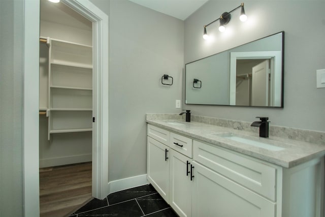 519 W James St, Wills Point, TX 75169 - bathroom with double vanity, baseboards, a walk in closet, and tile patterned flooring