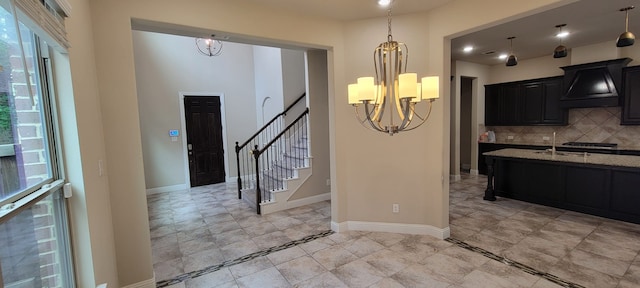 3805 Bentley Dr, Bedford, TX 76021 - kitchen featuring a chandelier, premium range hood, dark cabinetry, tasteful backsplash, and light stone countertops