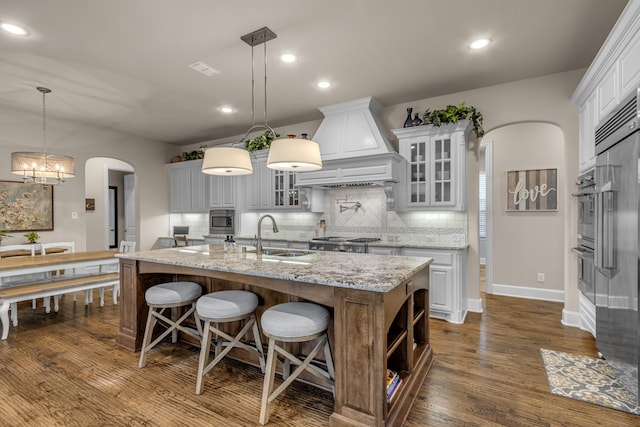 444 Francie Way, Allen, TX 75013 - kitchen featuring a sink, custom exhaust hood, arched walkways, built in appliances, and a kitchen island with sink