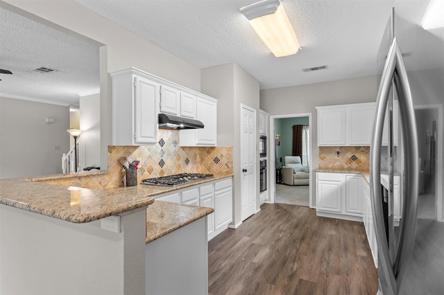 2804 Laurel Hill Dr, Flower Mound, TX 75028 - kitchen with stainless steel appliances, under cabinet range hood, a peninsula, a textured ceiling, and dark wood-style floors