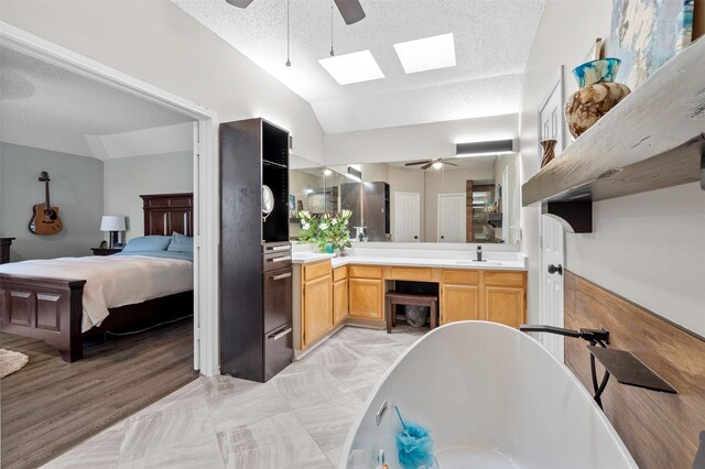 2804 Laurel Hill Dr, Flower Mound, TX 75028 - ensuite bathroom featuring a ceiling fan, lofted ceiling, a skylight, a freestanding bath, and double vanity