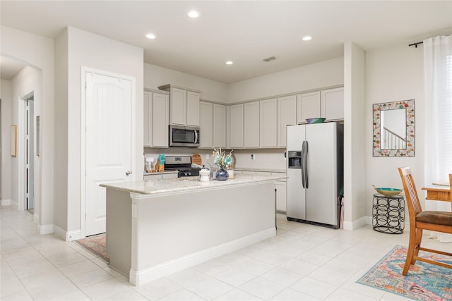 1909 Outpost Creek Ln, Aubrey, TX 76227 - kitchen with stainless steel appliances, a center island, light stone countertops, recessed lighting, and arched walkways